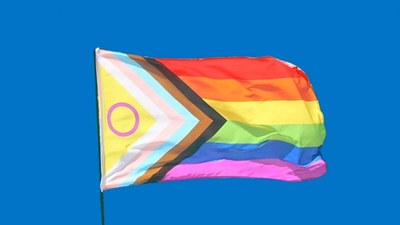 Una bandiera aquilone color arcobaleno che vola in un cielo blu